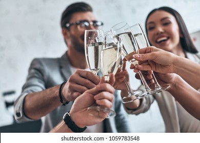 Colleagues and friends. Group of young business people toasting each other and smiling while standing in the board room