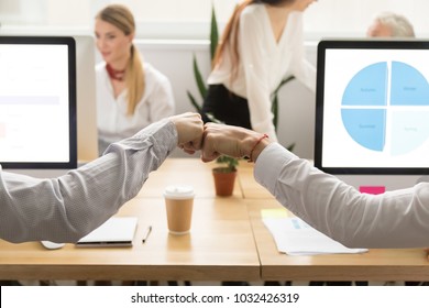 Colleagues giving fist bump, two male coworkers greeting, teammates celebrating corporate teamwork good result success concept, support in collaboration, friendship at work, close up view of hands