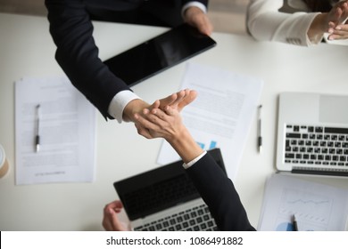 Colleagues giving high five above office desk celebrating good teamwork result or victory, motivated coworkers team join hands sharing business success, great collaboration concept, top close up view - Shutterstock ID 1086491882