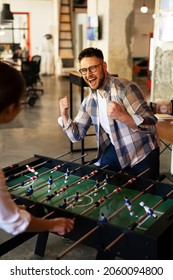 Colleagues Having Fun At Work. Businessman And Businesswoman Playing Table Soccer.	