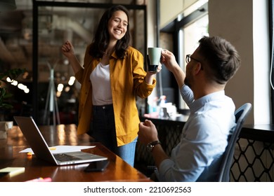 Colleagues laughing in office. Businesswoman and businessman drinking coffee