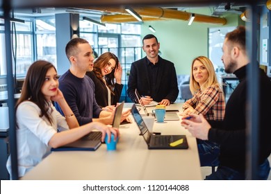 Colleagues looking at one man at the office meeting and smiling