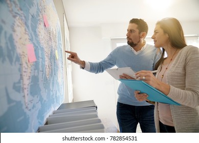 Colleagues in office looking at world map - Powered by Shutterstock