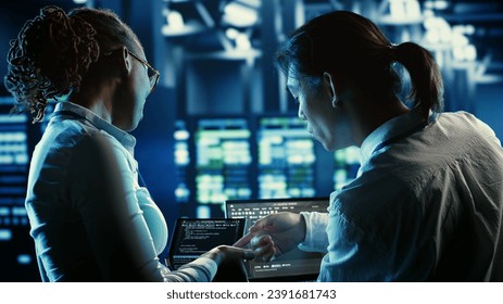 Colleagues programming in server farm housing advanced infrastructure storing massive datasets. Admins running code on laptop to repair data center racks doing complex computational operations - Powered by Shutterstock - Get 15% off with code: PIKWIZARD15