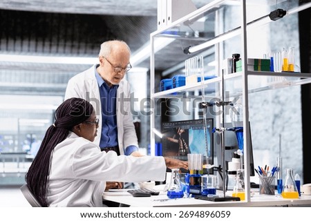 Colleagues in research lab analyzing flasks and chemical samples for experiment. Collaborative workspace highlighting innovation in biochemistry, nanotechnology for medical research.