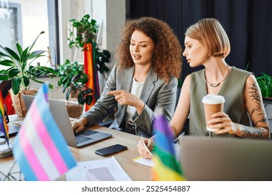 Colleagues share ideas over laptops while celebrating diversity in their workspace.