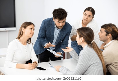 Colleagues sharing ideas and points of view, listening to each other while sitting around desk after advanced training course