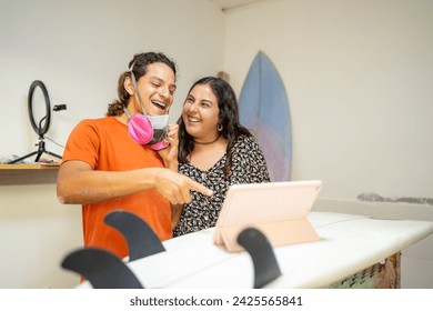 Colleagues of a surfboard repair shop in an online meeting with a digital tablet - Powered by Shutterstock