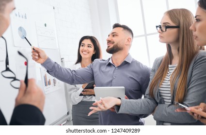 Colleagues Talking During Brainstorming Session On Whiteboard In Bright Office