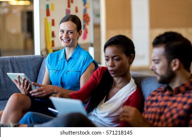 Colleagues using digital tablet and laptop while sitting on sofa in the office - Shutterstock ID 571218145