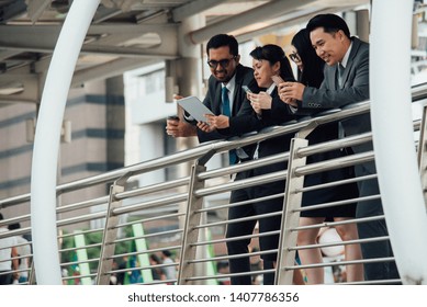Colleagues Using Mobile Phone While Standing By Railing