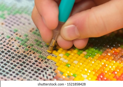 Collecting diamond embroidery, diamond mosaic. Colored crystals. Needlework. Creation. CloseUp.