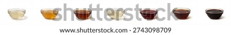 Collection of 7 different culinary vinegars and acids in glass bowls isolated on white. Assortment includes balsamic, apple cider, rice, white wine, red wine, sherry, and malt vinegar.