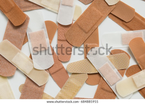 A collection adhesive bandages of various colors\
and shapes.