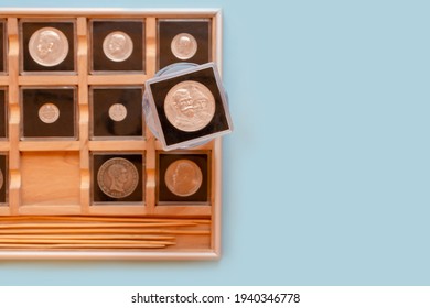 Collection of antique coins in plastic cases in wooden coin album. Numismatist metal coins in transparent cases on blue background. Selective focus
