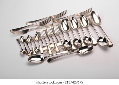 A collection of antique silver flatware. Photographed on a light background.