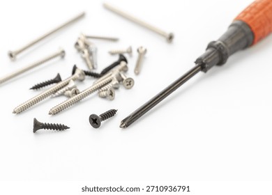 A collection of assorted screws and a screwdriver are spread across a clean white background. The screws vary in size and color, showcasing their detailed threads.