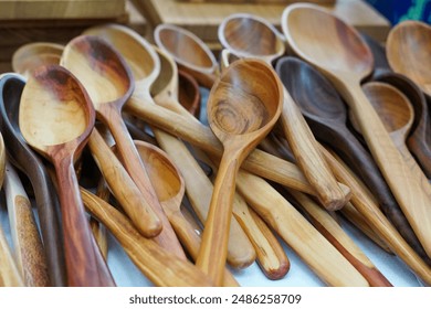 A collection of beautifully handcrafted wooden spoons displayed at an artisan market. The photo captures the rich textures and natural wood grains of the spoons - Powered by Shutterstock