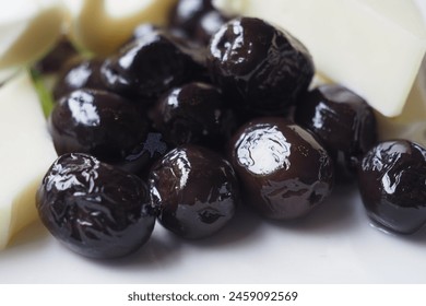 Collection of black olives with cheese on a plate .