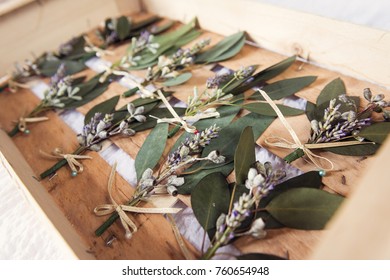A collection of boutonniere accessory pins, waiting for the best men groomsmen in a wooden rustic crate. Bohemian unique wedding.