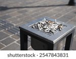 The collection of cigarette butts found in the outdoor ashtray on a public street