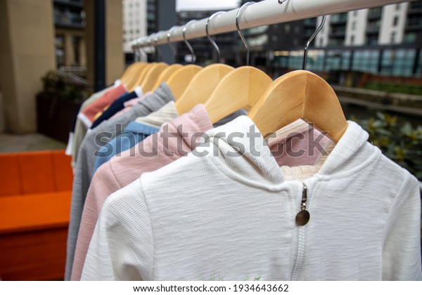 A collection of clothes on a clothes rail\
outside at a car boot sale or yard\
sale