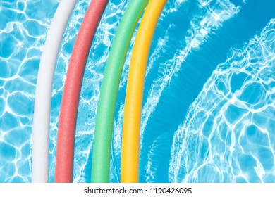 A collection of colorful noodle floatation devices in a pool water. 