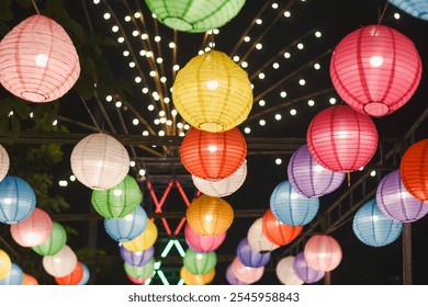 collection of colorful paper lanterns hanging from above, illuminated against a dark night sky.  - Powered by Shutterstock