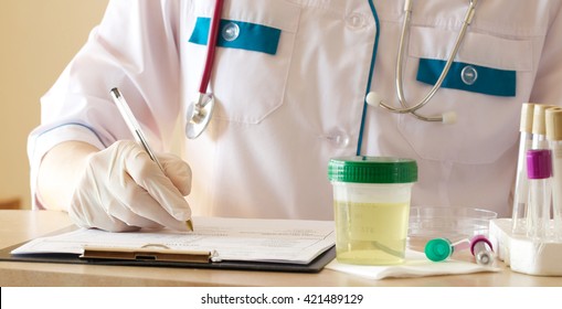 Collection Cup Of Urine Specimen On A Table Of A Lab Technician. 