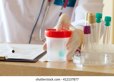 Collection Cup For Urine Test On A Table Of A Lab Technician. 