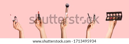Collection of different makeup products in female hands, collage on pink background. Panorama