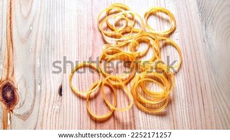 Collection of elastic yellow rubber bands to tie many things, and reusable, on woodenbackground