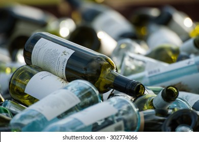 Collection of empty wine bottles of various colours piled in disorder in bin