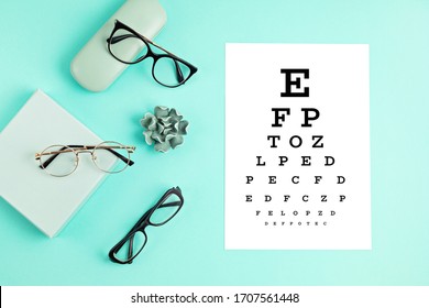 Collection of eyeglasses with eye test table. Optical store, glasses selection, eye test, vision examination at optician, fashion accessories concept. Top view, flat lay