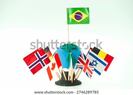 A collection of flags from various countries is placed around a small globe. The Brazilian flag is situated at the top, showing international diversity in this setup.