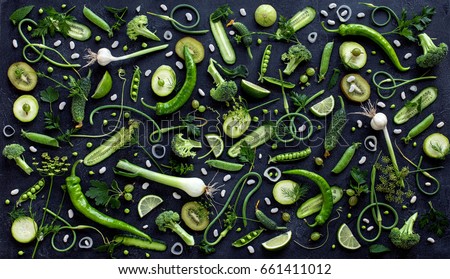 Collection of fresh green fruit and vegetables on the black wooden table, top view