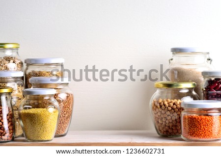 Collection of grain products in storage jars in pantry. Copyspace background.