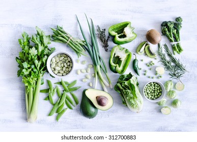 Collection Of Green Produce From Farmers Market On Rustic White Background From Overhead, Broccoli, Celery, Avocado, Brussel Sprouts, Kiwi, Pepper, Peas, Beans, Lettuce,