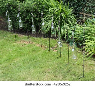 A Collection Of Hanging Glass Bottle Candle Holders.