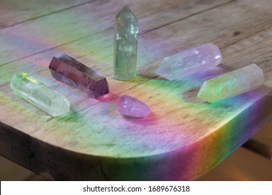 Collection of healing crystals on wood table with vibrant rainbow spectrum background. Healing aura of natural gems. Variety of crystal prisms for meditation and energy healing. Radiant magic gems.