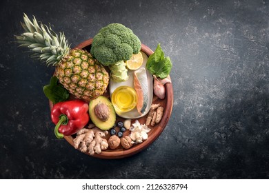 Collection of healthy food with anti-inflammatory and antioxidant on a wooden plate, immune system diet with fiber, vitamin, omega-3 and minerals, dark gray background, copy space, top view from above