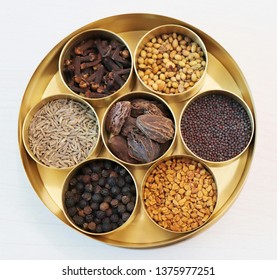 collection of Indian spices or Garam Masala like cumin seeds, coriander, Fenugreek, big cardamom, black pepper, cloves, mustard seeds in designer brass container on wooden background - Powered by Shutterstock