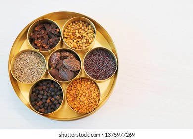 collection of Indian spices or Garam Masala like cumin seeds, coriander, Fenugreek, big cardamom, black pepper, cloves, mustard seeds in designer brass container on wooden background - Powered by Shutterstock