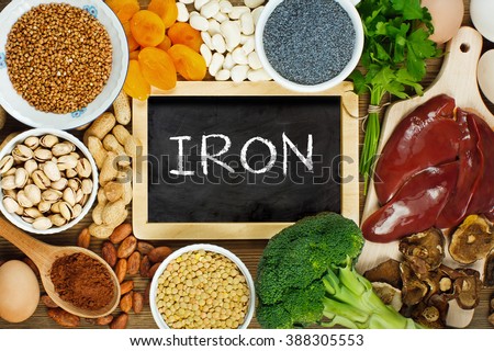 Collection iron rich foods as liver, buckwheat, eggs, parsley leaves, dried apricots, cocoa, lentil, bean, blue poppy seed, broccoli, dried mushrooms, peanuts and pistachios on wooden table.