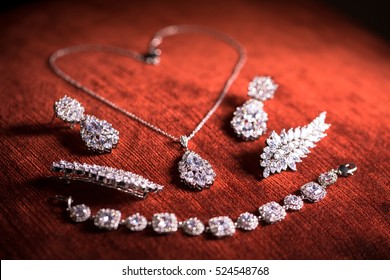 Collection of jewellery with diamond necklace and earrings on red velvet background