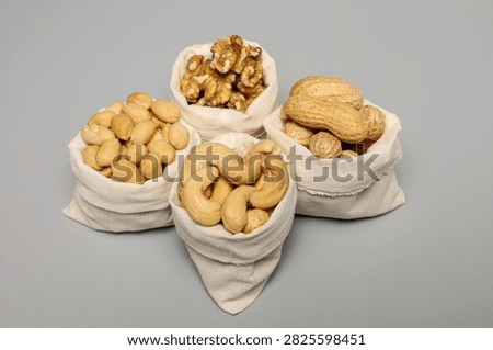 Collection of mixed nuts in mini cotton bags grouped together on grey backdrop