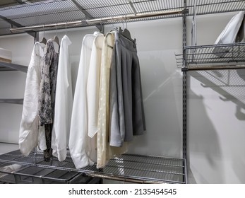 Collection Of Monotone Colors Tops And Bottoms Hanging Inside An Organized Walk In Closet With Metal Wire Rack Shelving