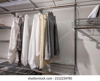 Collection Of Monotone Colors Tops And Bottoms Hanging Inside An Organized Walk In Closet With Metal Wire Rack Shelving