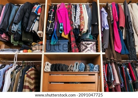 Collection of multicolored assorted clothes placed accurately on rails and hangers with shelves in walk in closet