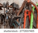 Collection of old, rustic hand tools and equipment hanging on a wall in a traditional workshop